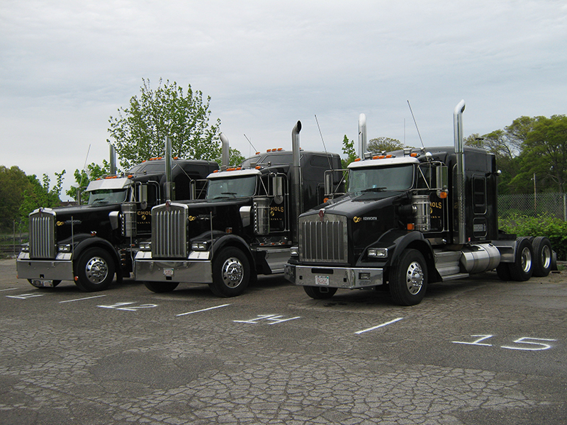 Trucks parked in marked spaces on a paved, fenced commercial lot in Middleboro, Massachusetts